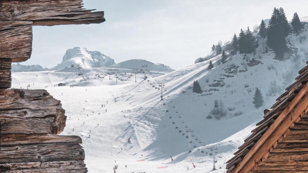 vue sur les pistes du grand bornand derrière les chalets typiques